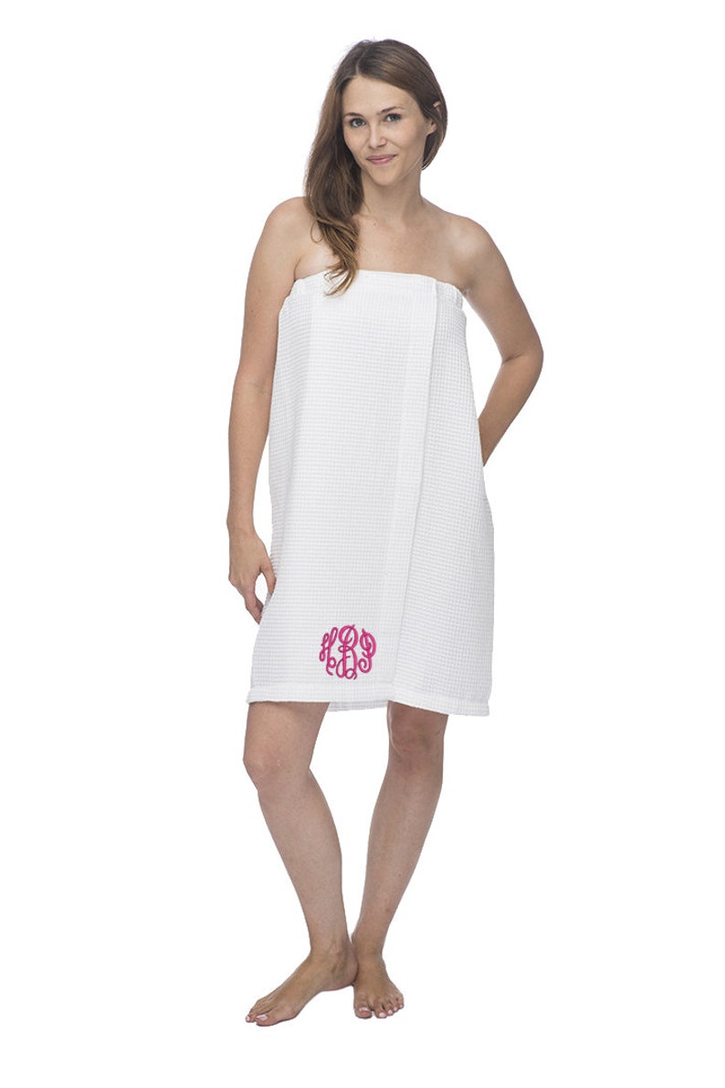 May include: White waffle weave bath wrap with a pink monogram. The wrap is worn by a person standing on a white background.