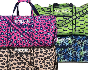 May include: Four different duffel bags with personalized names. The bags are in various animal print patterns, including leopard, alligator, and a blue and green pattern. The bags have black straps and zippers.