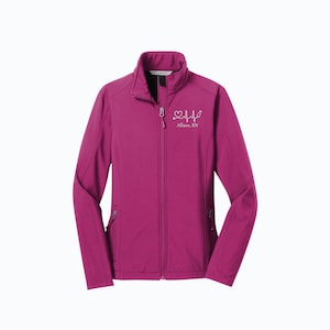 May include: A pink soft-shell jacket with a zipper closure. The jacket has a white embroidered heart with a stethoscope and a heartbeat line. The text "Allison, RN" is embroidered below the heart.