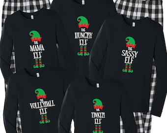 May include: Black long-sleeved shirts with a Christmas elf graphic and the text "The Mama Elf", "The Hungry Elf", "The Sassy Elf", "The Volleyball Elf", and "The Tinker Elf".