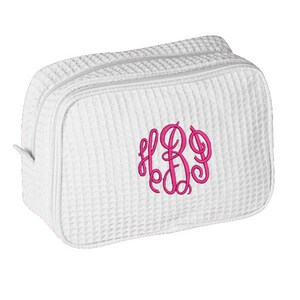 May include: White quilted makeup bag with a pink monogram of the letters "HBD".