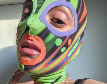 Funky colorful printed fabric mask in green, orange and purple tones. Abstract print and motifs.