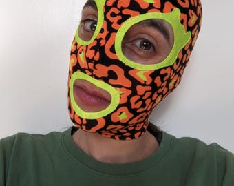 Funky orange print fabric mask with neon yellow eye and lips contours.