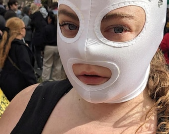 White fabric mask with decorative silver round pearls sewn across the forehead.