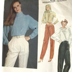 May include: Vintage Vogue International Designers sewing pattern featuring Gianni Versace designs. The pattern includes illustrations of women's clothing, including a blue blouse and white trousers, and other outfits in shades of orange and black.