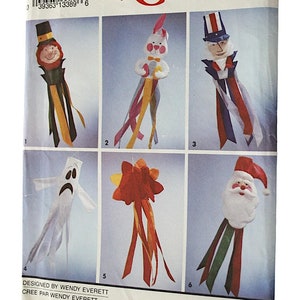 May include: Simplicity Crafts pattern with six craft designs: a leprechaun, a bunny, Uncle Sam, a ghost, a bow, and Santa Claus. Each design has colourful ribbons. The pattern is designed by Wendy Everett. The measurements are in centimetres.