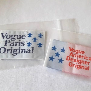 May include: Two white fabric labels with blue and red text. The first label says "Vogue Paris Original" with blue stars. The second label says "Vogue American Designer Original" with red text and blue stars.