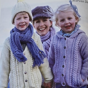 May include: A page from a knitting pattern book titled "Cardigans & Hats Design H Scarves Design". The image shows children wearing knitted cardigans, hats, and scarves. The book's contents are also visible, listing various knitting designs.