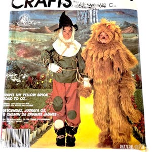 Puede incluir: Un patrón de costura vintage de McCall's Crafts para un disfraz de león y espantapájaros. El patrón es para las tallas 7-8 e incluye instrucciones para hacer ambos disfraces. La portada del patrón presenta una foto de dos niños usando los disfraces.