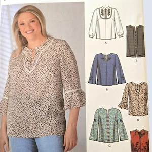 Op de afbeelding: Een Simplicity naaipatroon-envelop voor 6 eenvoudig te maken tops, maat GG 26W-32W. De voorzijde toont een model in een beige top met een klein donker patroon, een split-halslijn en klokmouwen. Illustraties van zes verschillende topontwerpen staan afgebeeld.