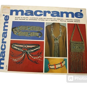 May include: A book cover with the title "macrame'" in blue letters. The cover features photos of macrame projects, including a belt, necklace, and bag. The text on the cover reads "An easy to follow illustrated guide for teachers and hobbyists completely covering basic macrame plus diagrammed patterns for 21 beautiful practical macrame projects."