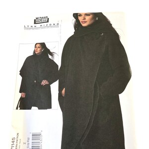 May include: A Vogue Patterns sewing pattern envelope for a Lynn Mizono design, labelled V1145, size Z (Lrg-Xlg). The envelope features a photograph of a dark charcoal coat with a wide collar, long sleeves, and a wrap-style front closure.