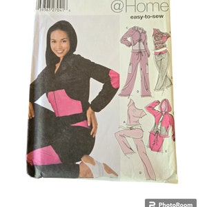 May include: Simplicity @Home sewing pattern number 353 for sizes 8-18. The pattern includes instructions for making a hooded sweatshirt, trousers, and a short-sleeved top. The pattern is illustrated with a woman wearing a black and pink hooded sweatshirt and trousers.