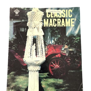 May include: A vintage book cover for a macrame craft project. The cover features a white macrame hanging with a bell-shaped top and tassels. The book title is "Classic Macrame" and the Canadian price is $2.49.