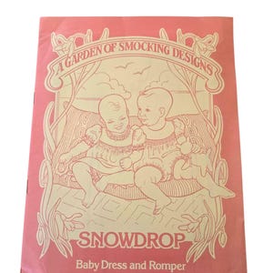 May include: A pink vintage sewing pattern titled "A Garden of Smocking Designs" featuring illustrations of two babies in dresses. The pattern is for a baby dress and romper, with the word "SNOWDROP" prominently displayed.