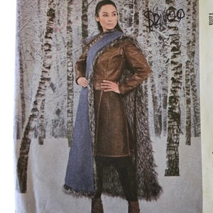 May include: A McCall's Costumes sewing pattern envelope M7855, size A5 (6-8-10-12-14). The cover features a photograph of a person wearing a brown leather-look jacket and a long, textured gray and brown faux fur cape in a snowy birch forest setting.