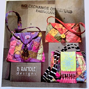 May include: Vogue accessories pattern featuring three fabric bag designs. The bags include a patchwork tote, a rectangular clutch with a button closure, and a striped tote with a fringed scarf detail. The pattern includes the text "B. Randle Designs."