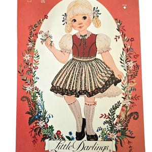 May include: A sewing pattern envelope titled Little Darlings designs from Enchanted Forest featuring an illustration of a blonde child in a red bodice and floral skirt. The text includes Size 3, 4, 5 or 6, 7, 8 and the number 122 on a red background.