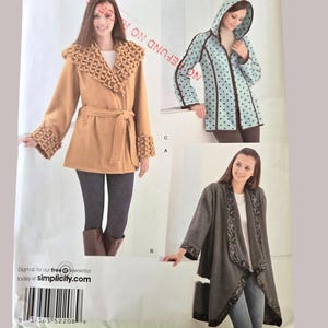 Peut inclure: Patron de couture Simplicity présentant trois modèles de manteaux. Le patron comprend un manteau beige avec un col et des poignets texturés, un manteau à capuche bleu à pois et un manteau gris avec des bordures décoratives. Le numéro du patron est 2011.