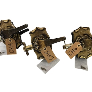 May include: Three antique brass door handles with a leaf design. Each handle has a lever and a decorative backplate. Each handle has a tag with the text "CH4", "CH5", and "CH6".