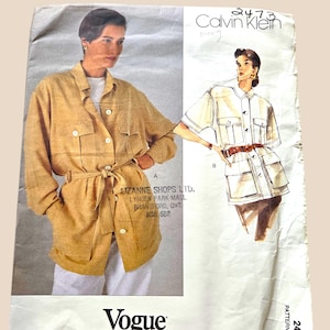 May include: A vintage Vogue Patterns sewing pattern featuring a Calvin Klein design. The pattern shows illustrations of a belted jacket and a short-sleeved shirt. The pattern includes the text "Vogue Patterns AMERICAN DESIGNER" and the number "2473".