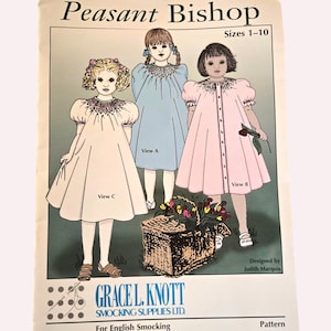 May include: A vintage sewing pattern titled "Peasant Bishop" for sizes 1-10. The pattern features illustrations of three different dress designs, labeled View A, B, and C. The pattern is designed by Judith Marquis and produced by Grace L. Knott Smocking Supplies Ltd.