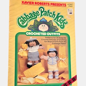 May include: A vintage "Cabbage Patch Kids" crochet pattern book. The cover is yellow with green and red accents, featuring two dolls in crocheted outfits. The text reads "CROCHETED OUTFITS" and "Patterns for 20 Easy-to- Crochet Articles of Clothing for Boys & Girls from the Cabbage Patch".