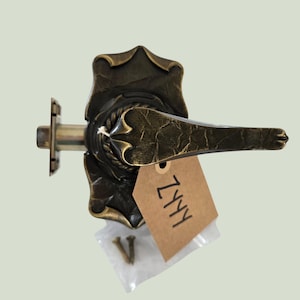 May include: Antique brass door handle with a decorative floral design. The handle has a lever style and includes a mounting plate and screws. A brown tag with the text "ZYYY" is attached.