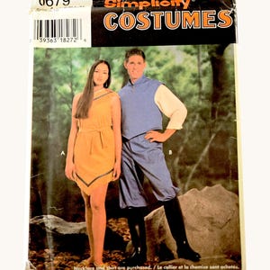 May include: A Simplicity Costumes sewing pattern envelope, number 0679, featuring two costume designs. Design A is a yellow sleeveless dress with fringe trim. Design B is a blue vest and blue pants worn with black boots. The text reads Simplicity COSTUMES.