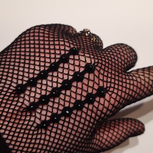 May include: Black fishnet gloves with black beads sewn on the back of the hand.
