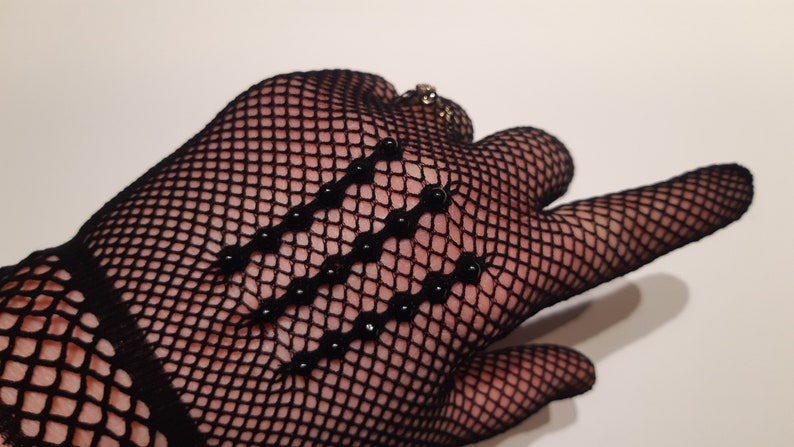 May include: Black fishnet gloves with black beads sewn on the back of the hand.