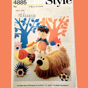 May include: Vintage sewing pattern featuring illustrations of soft toy characters from "The Magic Roundabout" TV series. The pattern includes a doll, a dog, and a snail, with the word "Style" at the top. The pattern is dated 1974.