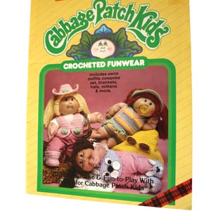 May include: A vintage Cabbage Patch Kids box showcasing crocheted funwear. The box features three dolls in crocheted outfits, including a cowpoke set, swim outfits, hats, and mittens. The text reads "Xavier Roberts Presents Cabbage Patch Kids Crocheted Funwear."