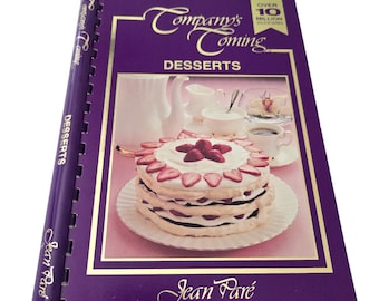 May include: A purple cookbook with a gold title "Company's Coming Desserts" by Jean Paré. The cover features a photo of a layered dessert with strawberries and whipped cream.