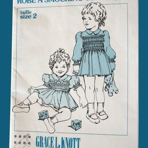 May include: A vintage sewing pattern for a classic yoke dress, size 2, with illustrations of two girls wearing the dress. The pattern is from Grace L. Knott Smocking Supplies Ltd. and is for English smocking.