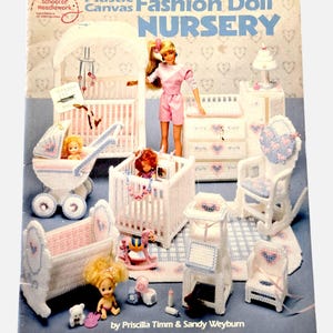 May include: A craft instruction book titled Plastic Canvas Fashion Doll Nursery by Priscilla Timm and Sandy Weyburn. The cover displays various white plastic canvas nursery furniture items, including a crib, stroller, and rocking chair, with dolls.