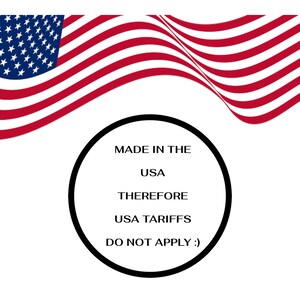 May include: The image shows the American flag waving in the background. A black circle contains the text "MADE IN THE USA THEREFORE USA TARIFFS DO NOT APPLY :)". The flag has red and white stripes and a blue field with white stars.
