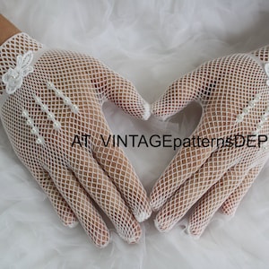 May include: A pair of white mesh gloves with pearl embellishments and a floral design. The gloves are held together in a heart shape.