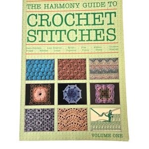 May include: A book titled "The Harmony Guide to Crochet Stitches, Volume One." The cover features the title in large green letters, with examples of crochet stitches in various colors and patterns. The book is on a white background.