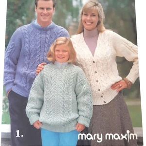 May include: A softcover knitting pattern book titled Aran Fashions Book II by Mary Maxim, featuring a cover photograph of three people wearing cable-knit sweaters and a cardigan with intricate textured patterns in blue, white, and light green.