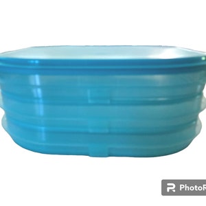 Peut inclure: Un récipient empilable en plastique bleu avec un couvercle. Le récipient est de forme ovale et comporte trois sections.