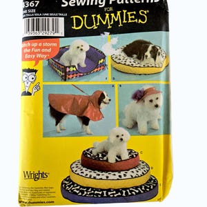 May include: Simplicity sewing pattern for dog beds, hats, and coats in three sizes. The package features images of dogs with the finished products, including a bed, raincoat, and hat. The text "Sewing Patterns for Dummies" is prominently displayed.