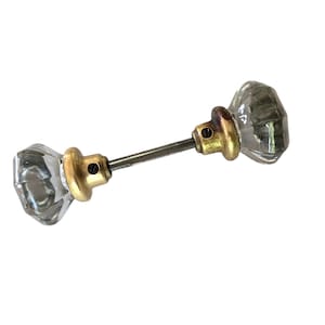 May include: A pair of clear glass door knobs with brass accents and a metal connecting rod.