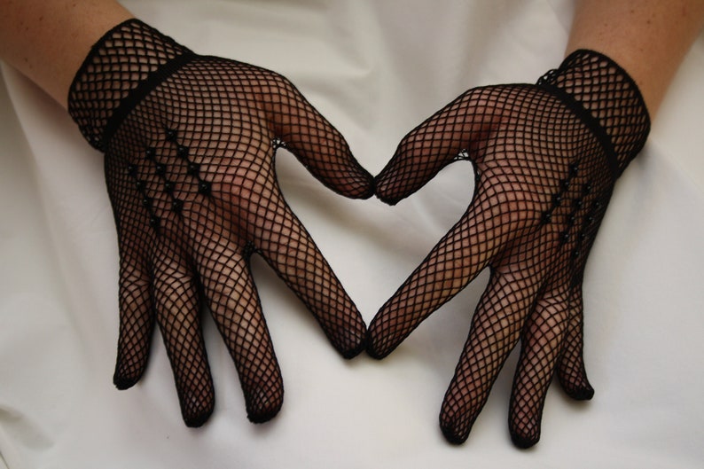 May include: A pair of black fishnet gloves with a heart shape formed by the hands.