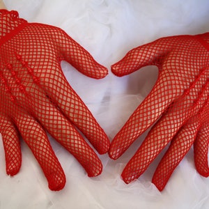 May include: A pair of red fishnet gloves with a heart shape formed by the hands.