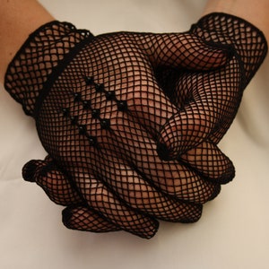 May include: A pair of black fishnet gloves with a delicate pattern. The gloves are made of a fine mesh material and have a close-fitting design.