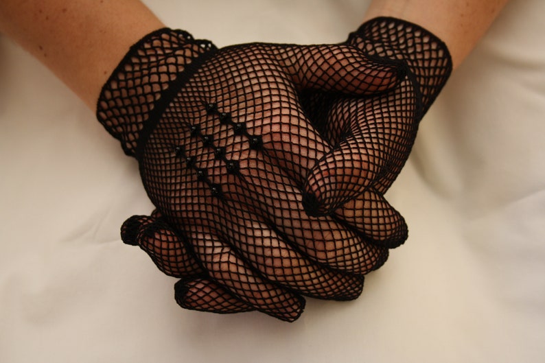 May include: A pair of black fishnet gloves with a delicate pattern. The gloves are made of a fine mesh material and have a close-fitting design.