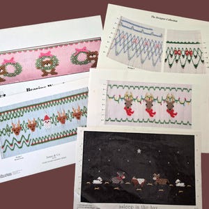 May include: A selection of Christmas cross-stitch patterns featuring festive designs. The patterns depict reindeer, Santa, teddy bears with wreaths, and sheep. The designs are printed on white paper with a brown backdrop.