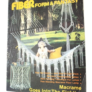 May include: A magazine cover featuring a white macrame hammock with a doll sitting in it. The cover text reads "Fiber Form & Fantasy Opus 3 Macrame Goes Into The Eighties".