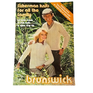 May include: A book cover with a photo of a couple wearing white fisherman knit sweaters. The book title is "Fisherman Knits for All the Family" and the subtitle is "An Aran Book of Irish Knits in Sizes 4 to 46". The book is published by Brunswick.